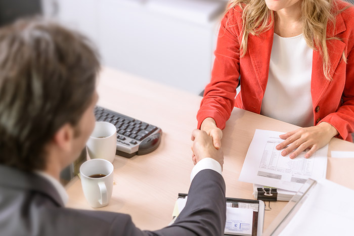lawyer and client shake hands across the desk