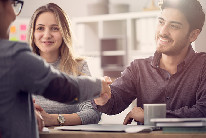 young couple shakes hands with lawyer across the desk
